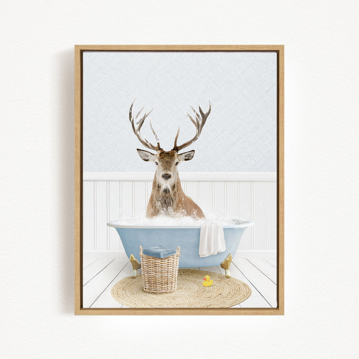 A deer with large antlers is sitting in a blue bathtub filled with water, surrounded by a basket and a yellow rubber duck.