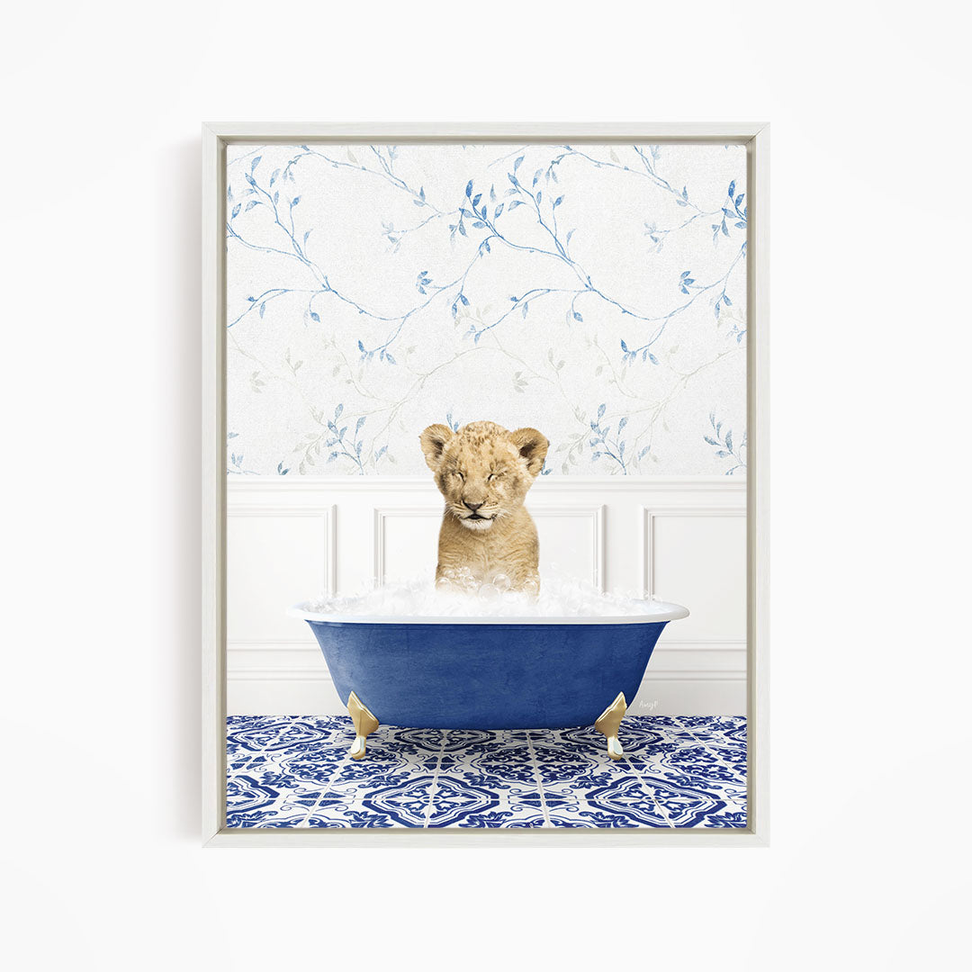 A young lion cub sitting in a blue bathtub filled with water, surrounded by a blue and white patterned floor.