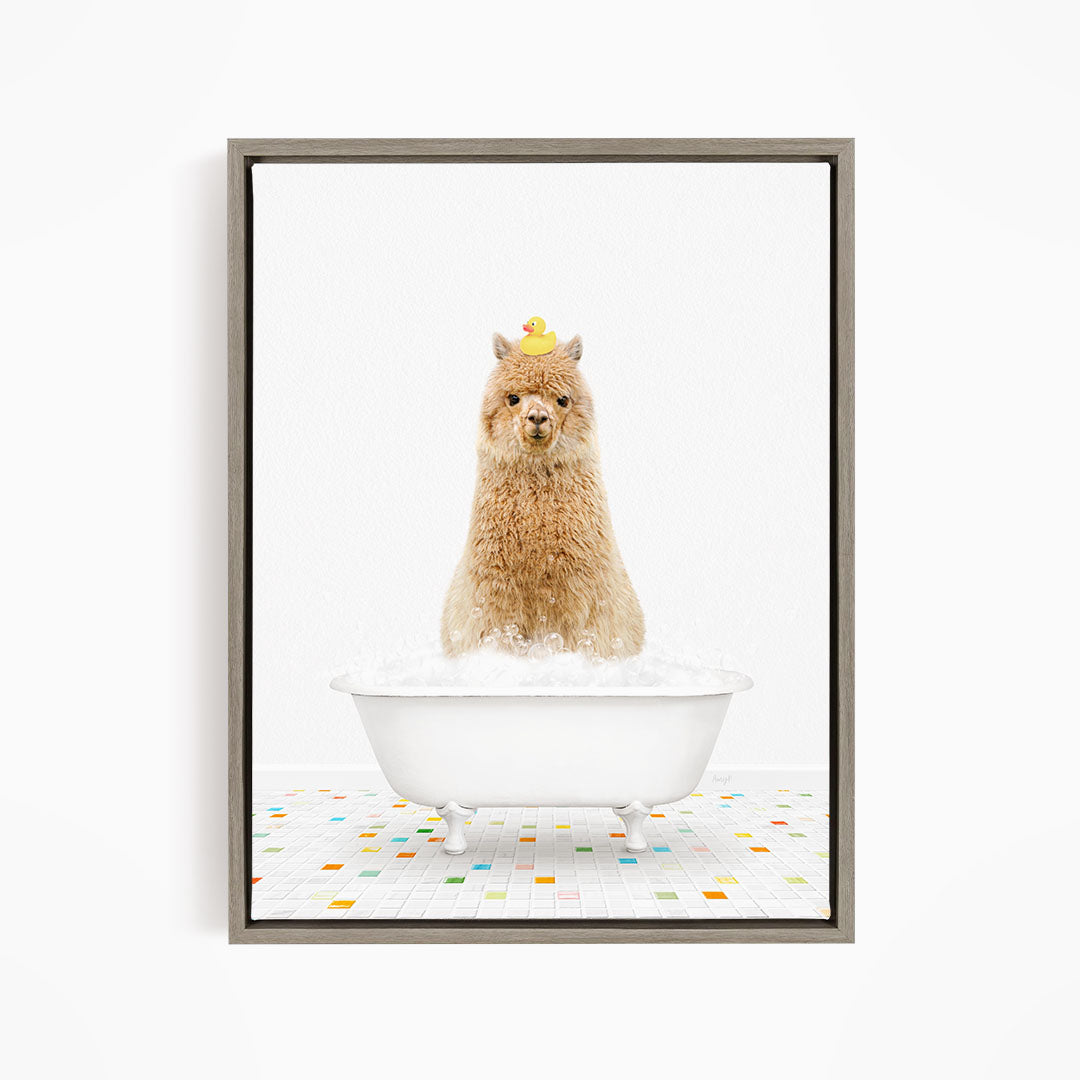 A fluffy brown alpaca sits in a white bathtub filled with bubbles, with a yellow rubber duck perched on its head.