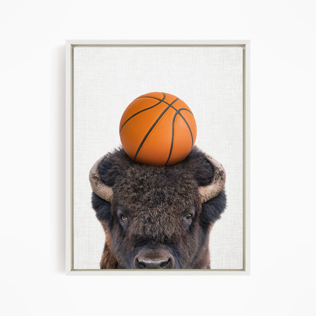 A buffalo with a basketball resting on its head.