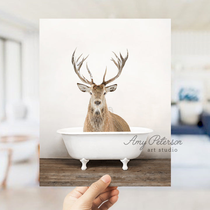 a hand holding up a photo of a deer in a bathtub