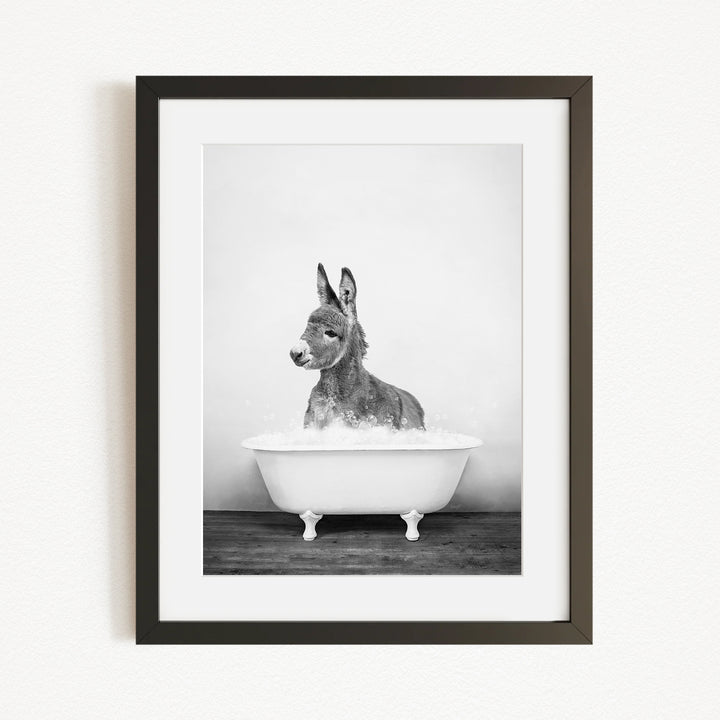 A donkey is sitting in a bathtub filled with water, creating a playful and whimsical scene.