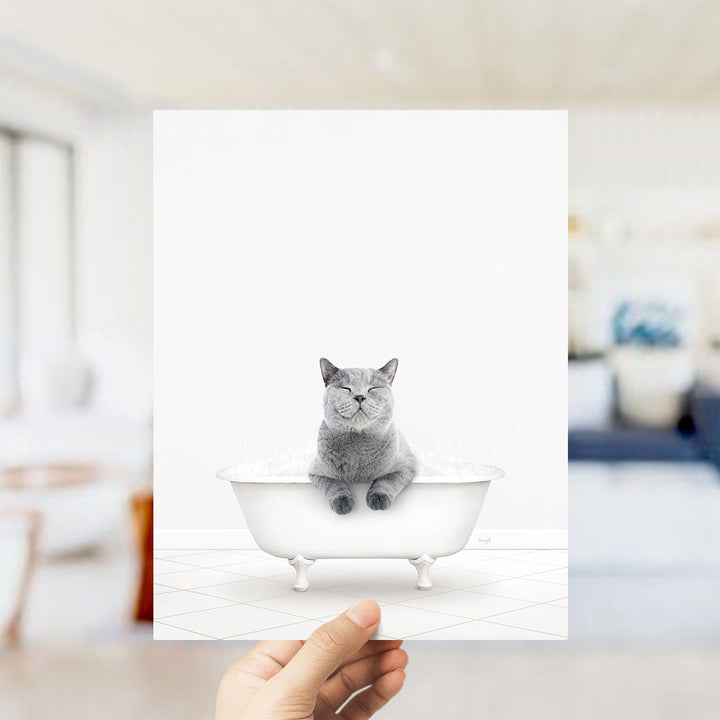 A gray cat sitting in a white bathtub filled with bubbles, with its eyes closed and appearing to be enjoying the bath.