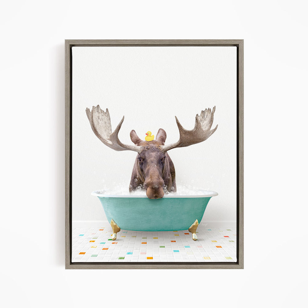 A moose with large antlers is sitting in a green bathtub, with a rubber duck floating on its head.