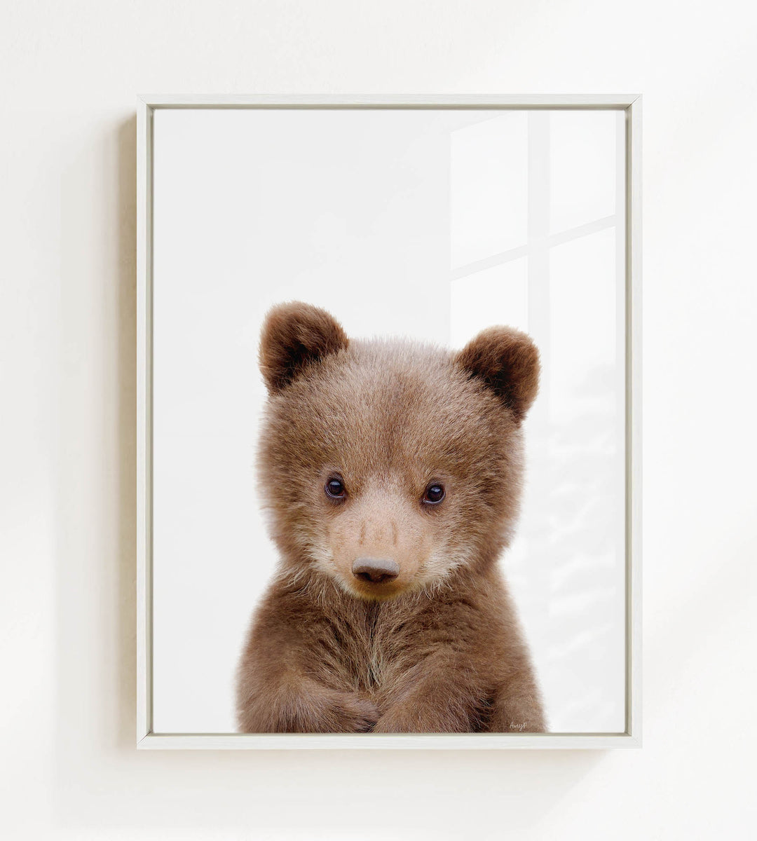 A cute brown bear cub with large eyes and a curious expression is the focus of the image.