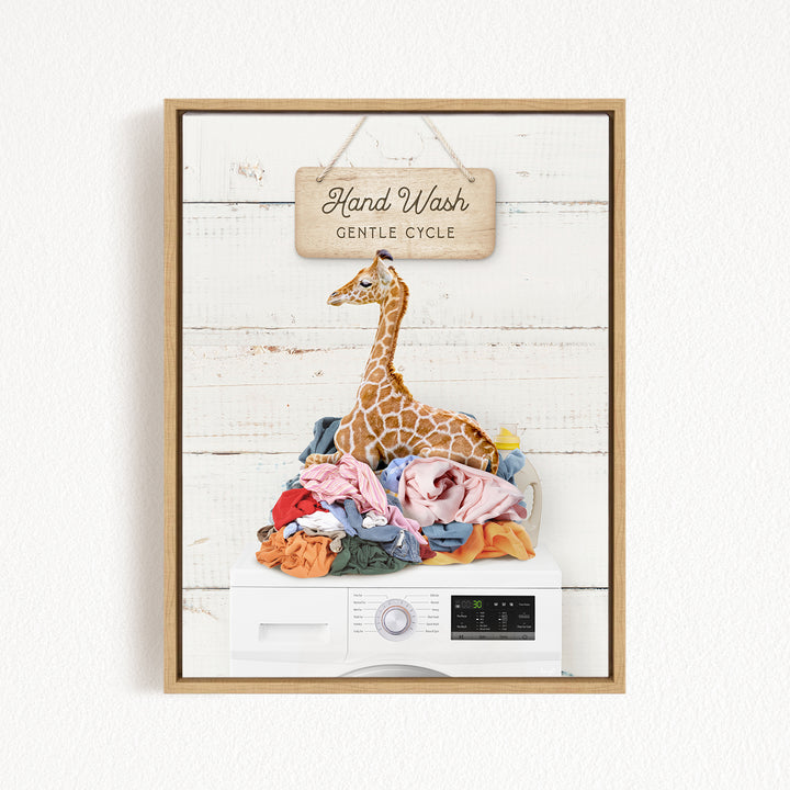 A giraffe sitting atop a pile of laundry, with a sign above that reads "Hand Wash Gentle Cycle".