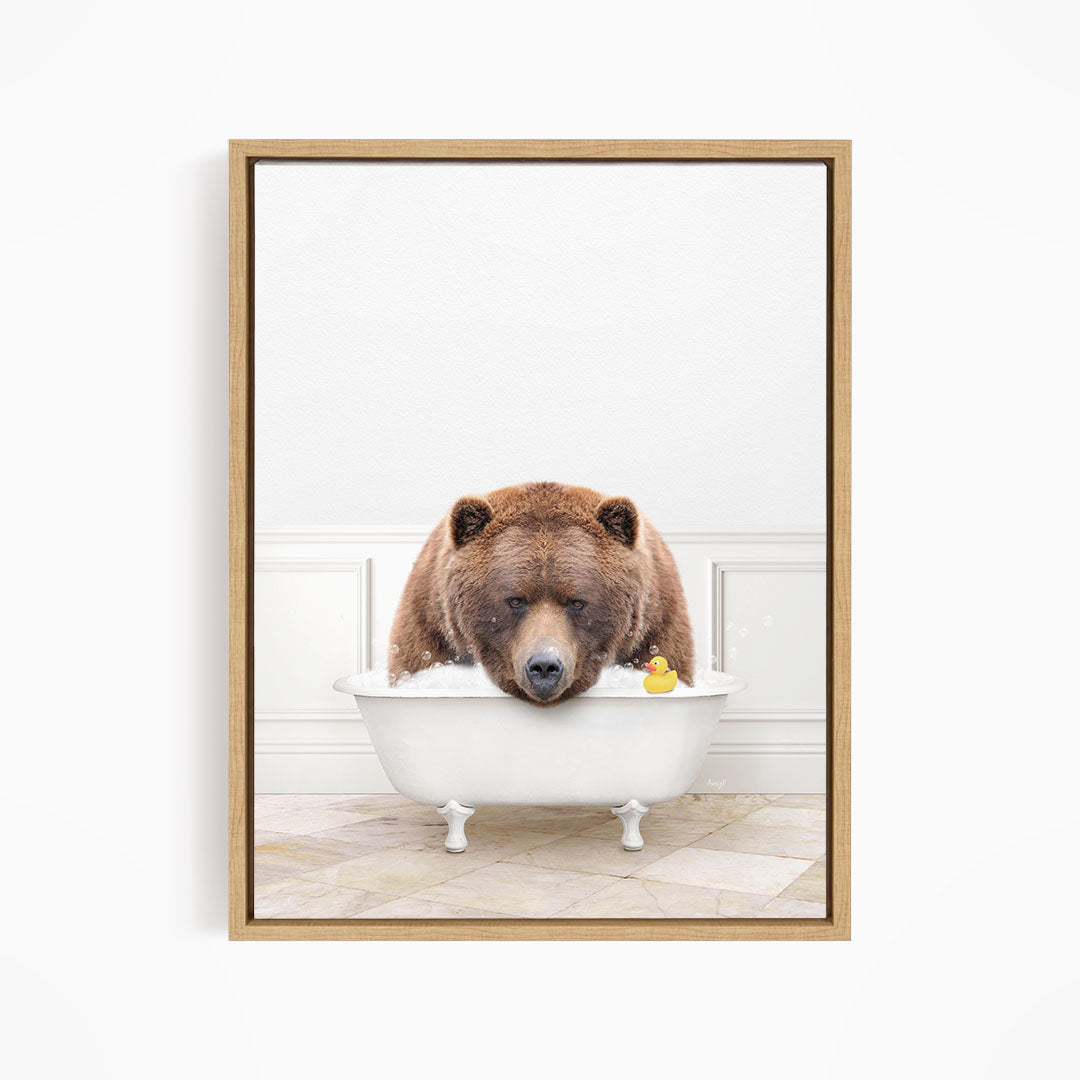 A brown bear is sitting in a white bathtub, with a rubber duck floating in the water.