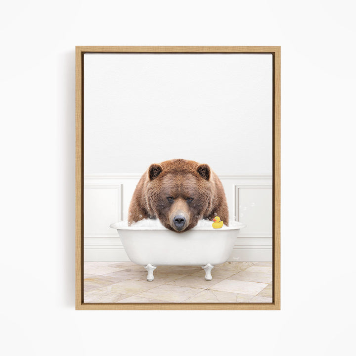 A brown bear is sitting in a white bathtub, with a rubber duck floating in the water.