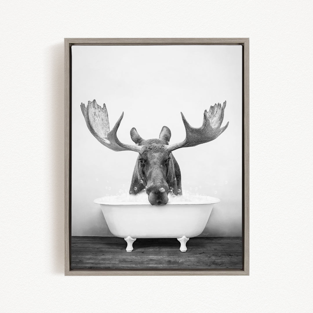 A moose with large antlers is sitting in a bathtub filled with water, creating a whimsical and humorous scene.