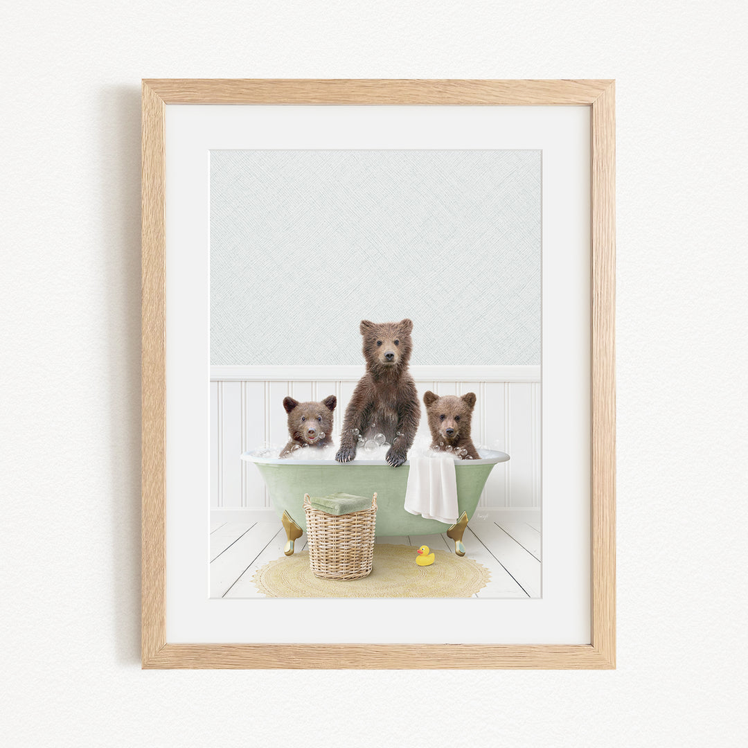 A framed image depicting three bears sitting in a green bathtub, with a yellow rubber duck floating in the water.