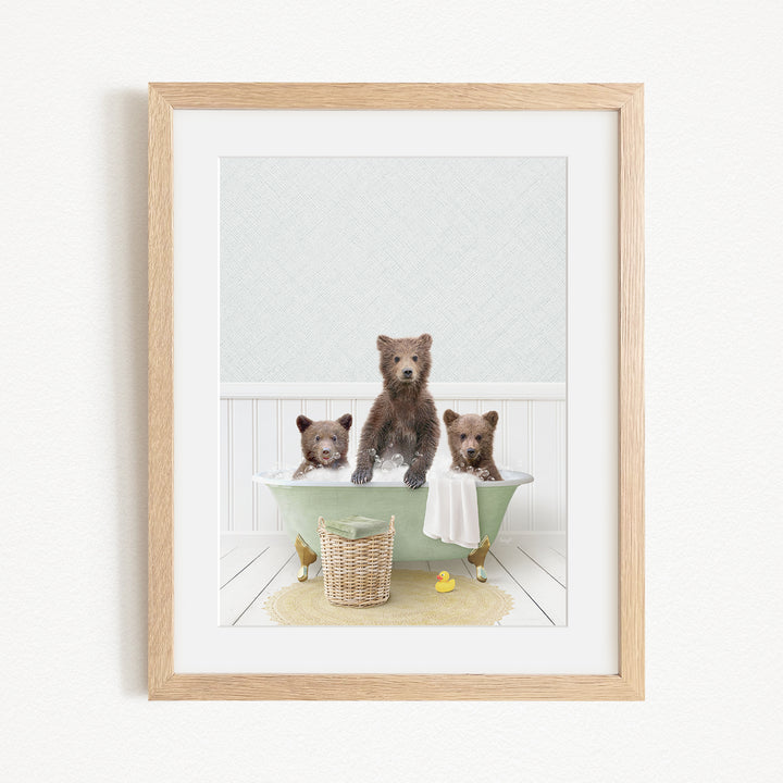 A framed image depicting three bears sitting in a green bathtub, with a yellow rubber duck floating in the water.