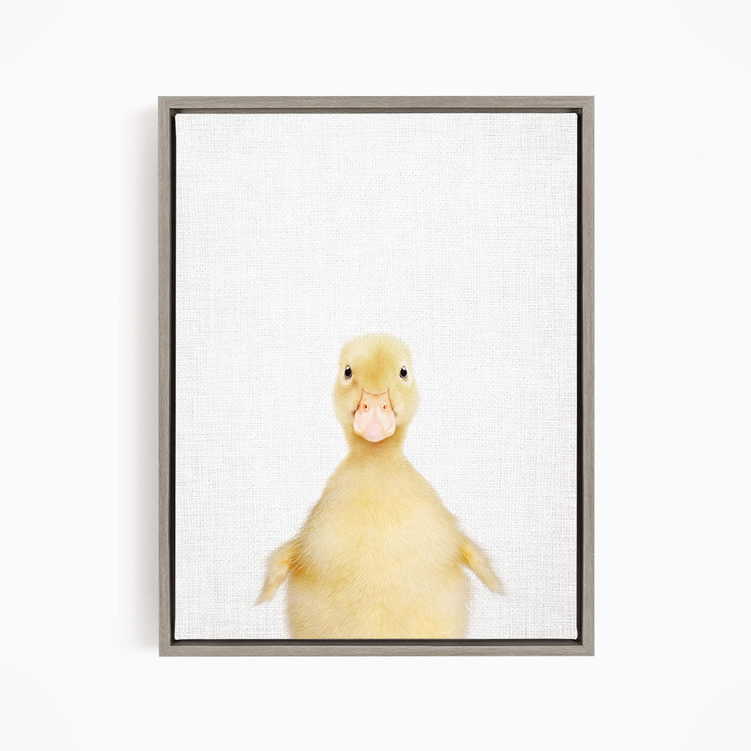 A cute yellow duck with a pink beak and eyes is looking directly at the camera.
