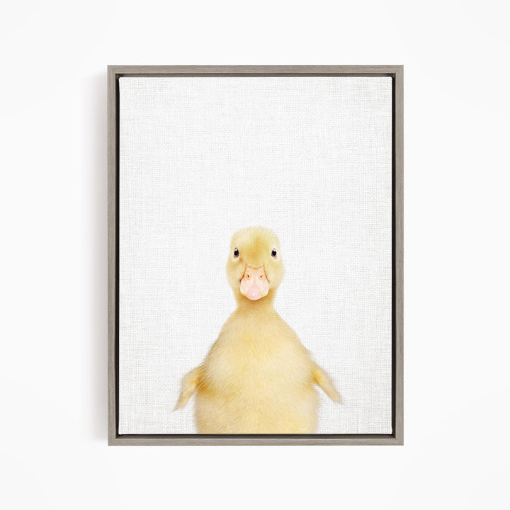 A cute yellow duck with a pink beak and eyes is looking directly at the camera.