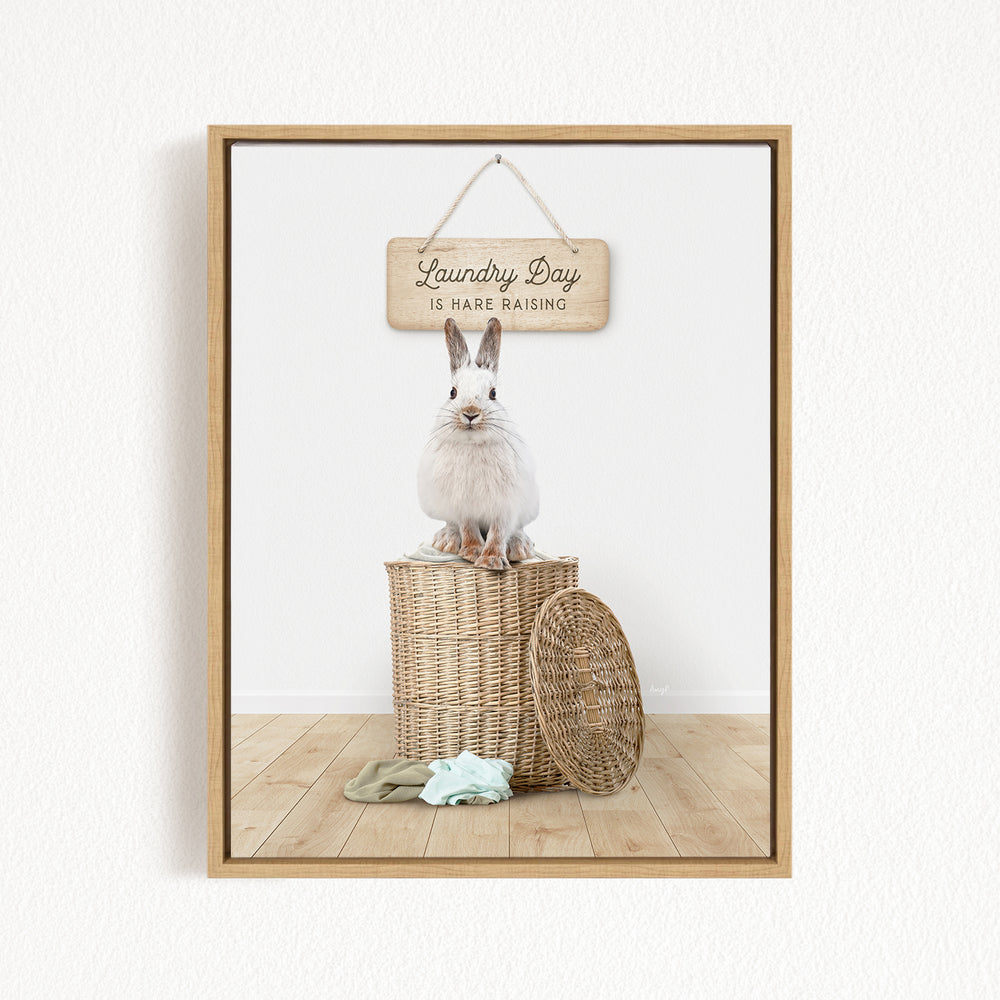 A white rabbit sits atop a wicker basket, with a wooden sign above that reads "Laundry Day is here raising".