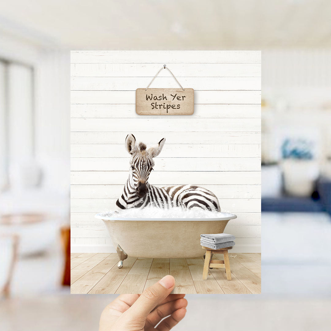 A zebra lying in a bathtub with a sign that says "Wash Yer Stripes" above it.