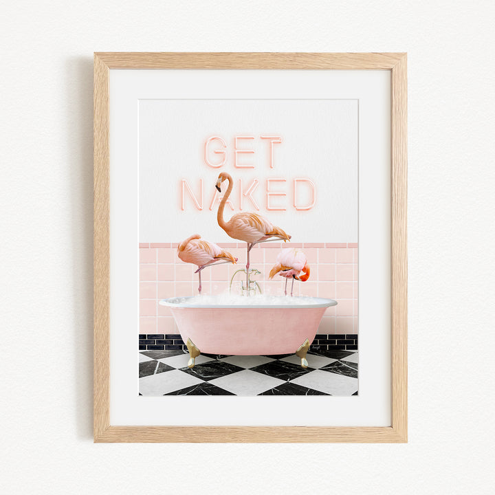 A framed image depicting three flamingos sitting in a pink bathtub, with the text "GET NAKED" displayed above them.