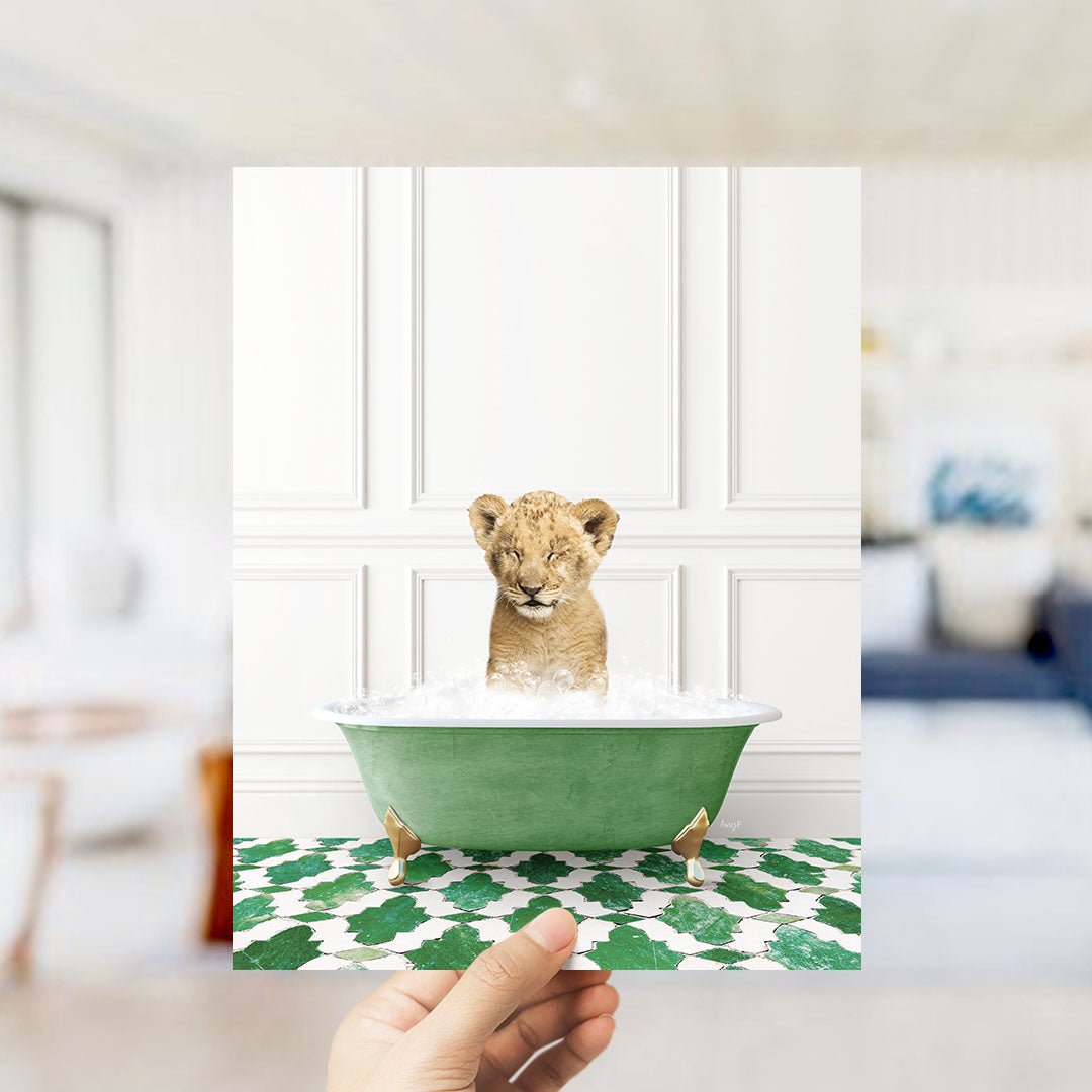 A young lion cub sitting in a green bathtub filled with water, surrounded by a patterned floor.