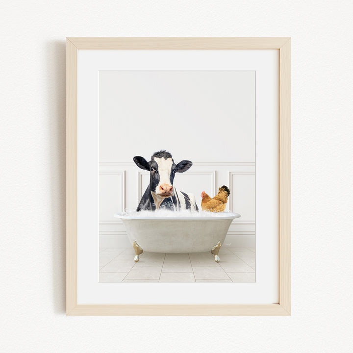 A black and white cow is sitting in a white bathtub, with a chicken standing nearby, in a white-walled room.