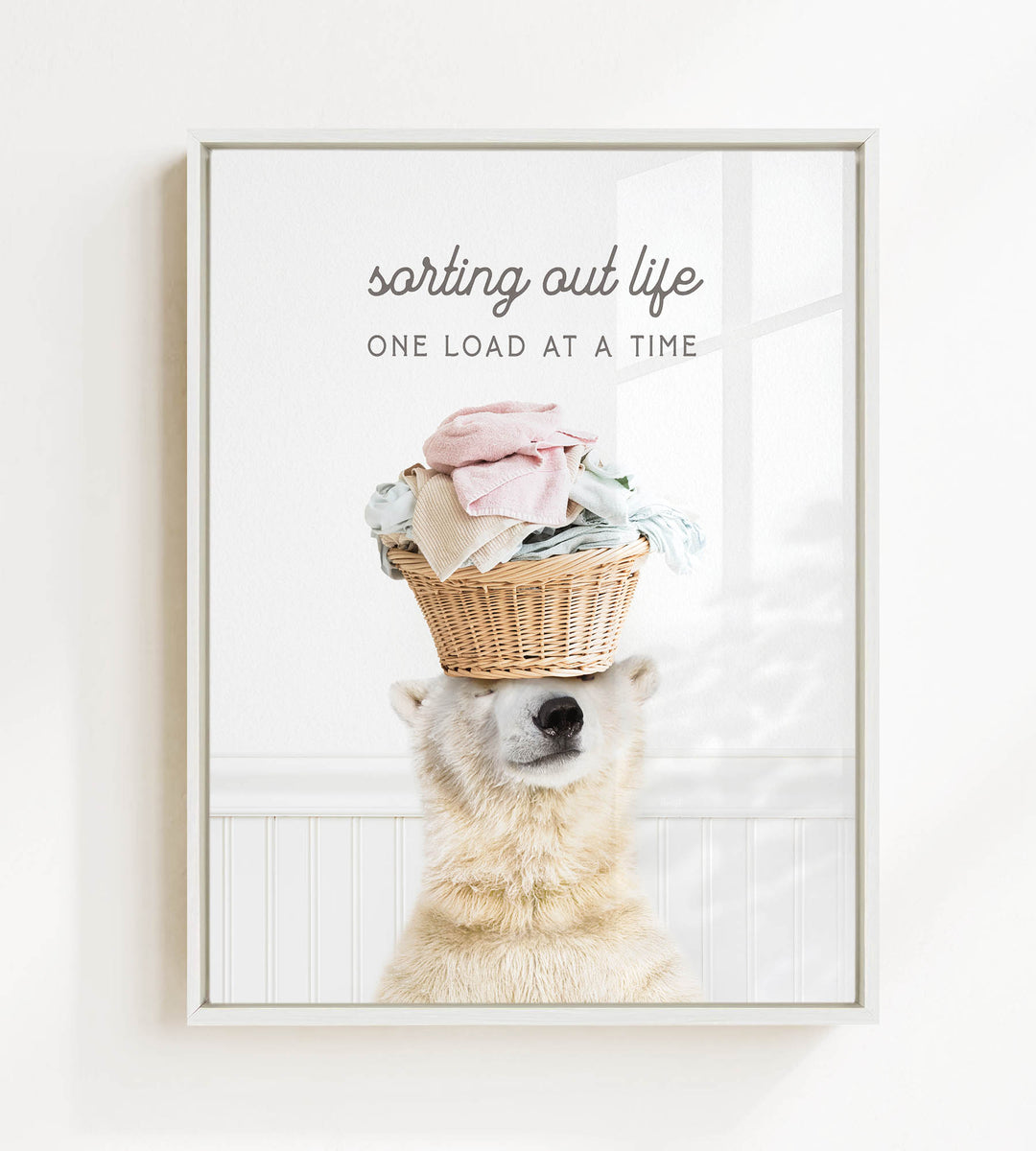 A polar bear balancing a basket of laundry on its head, with the text "sorting out life" and "ONE LOAD AT A TIME" displayed above the image.