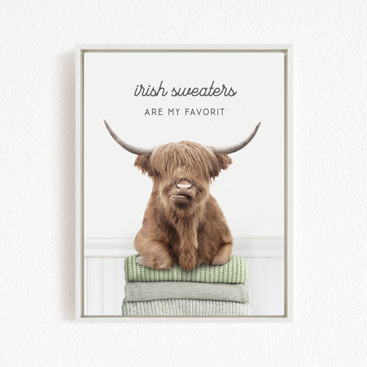 a brown cow with long horns sitting on a stack of green blankets.