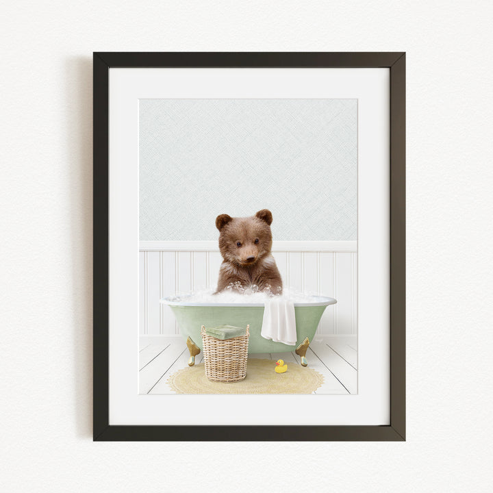 A cute brown bear sitting in a green bathtub, surrounded by a basket of toys and a yellow rubber duck.