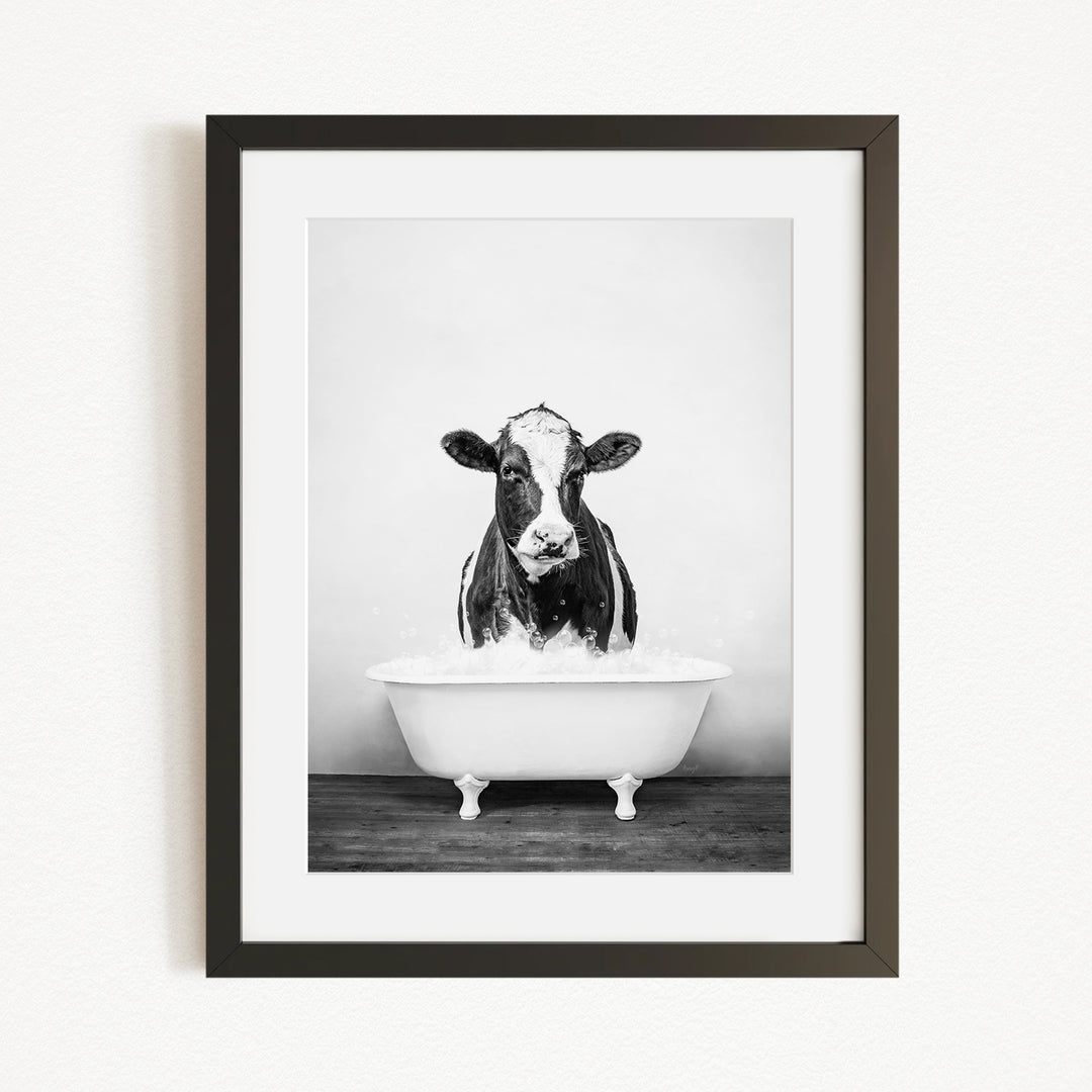 A black and white photograph of a cow standing in a bathtub filled with water.