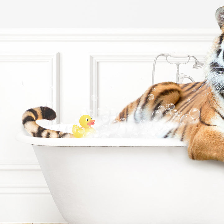 a stuffed tiger sitting in a bathtub next to a rubber duck