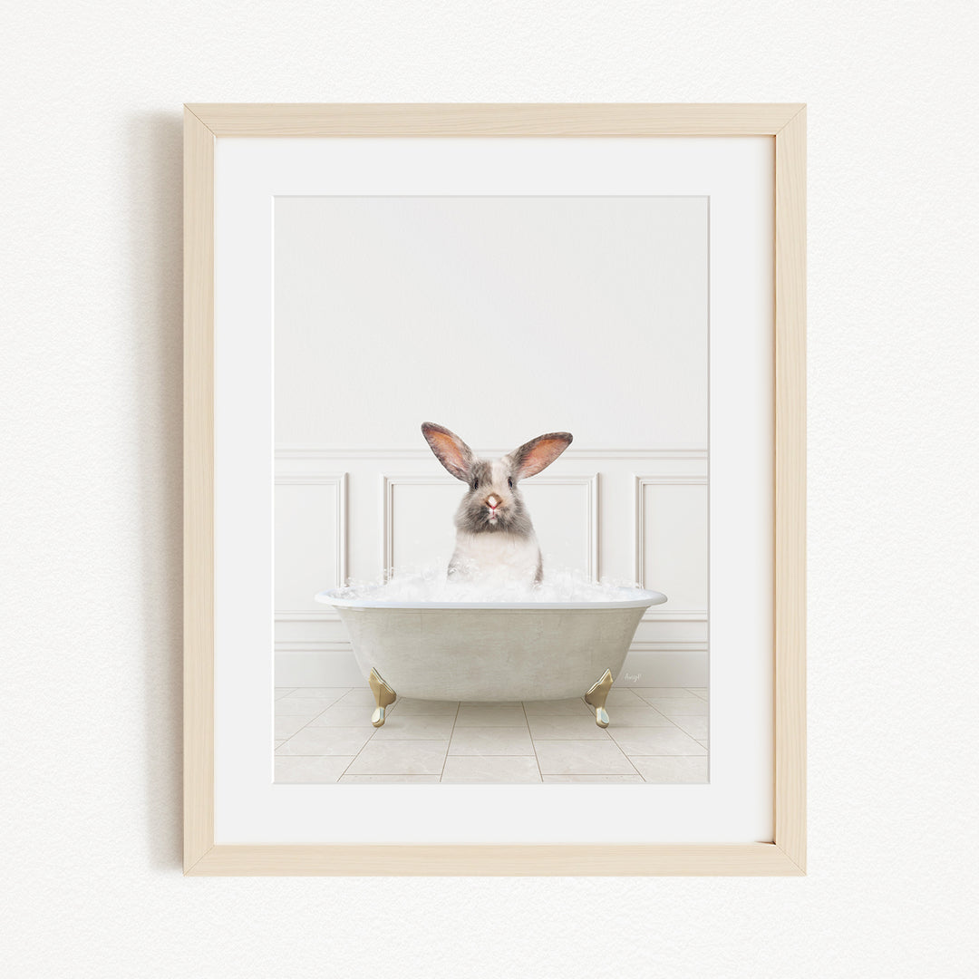A white rabbit sitting in a white bathtub filled with bubbles, looking directly at the camera.
