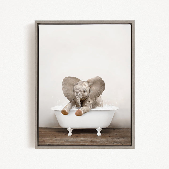 A baby elephant sitting in a white bathtub filled with water, with its trunk raised and ears spread out.