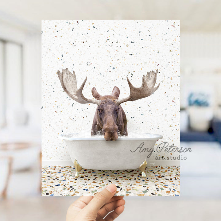 a hand holding up a card with a moose head in a bathtub