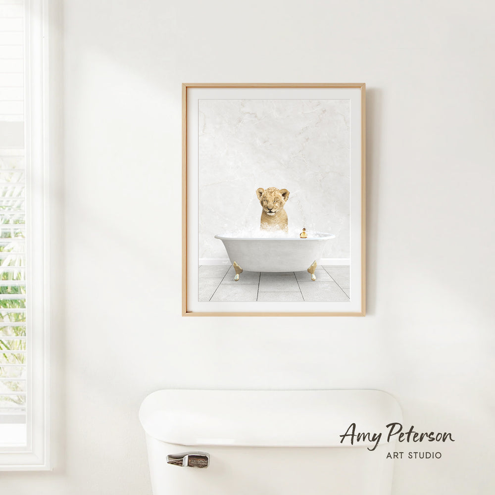 A framed print of a lion sitting in a bathtub is hanging on a white wall above a white toilet.