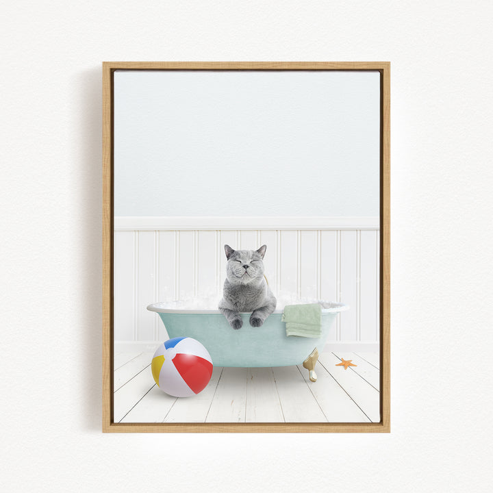A gray cat sitting in a blue bathtub, surrounded by a beach ball, towel, and starfish, creating a whimsical and playful scene.