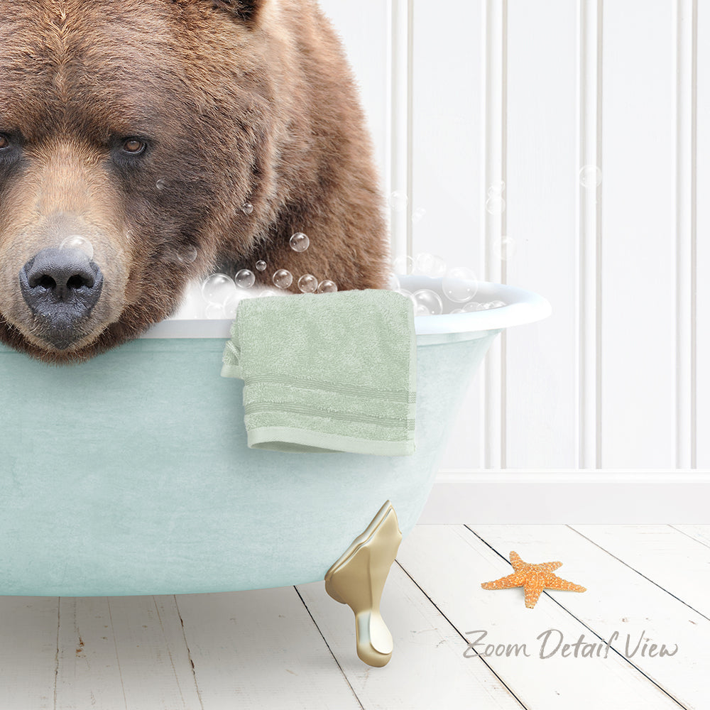 A brown bear is sitting in a light blue bathtub filled with bubbles, with a green towel and a starfish nearby.