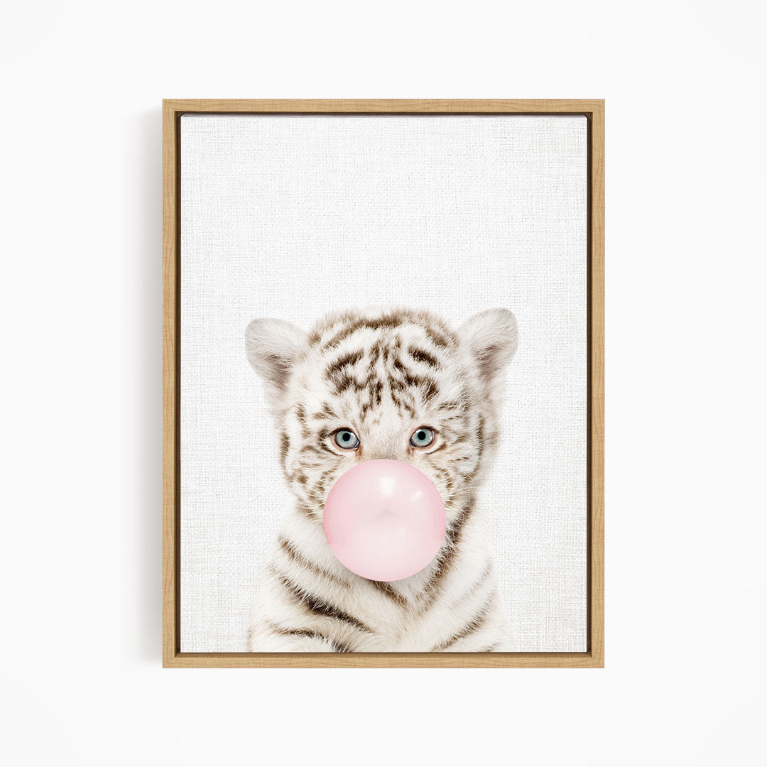 A young tiger cub blowing a bubble with a pink bubble gum bubble.