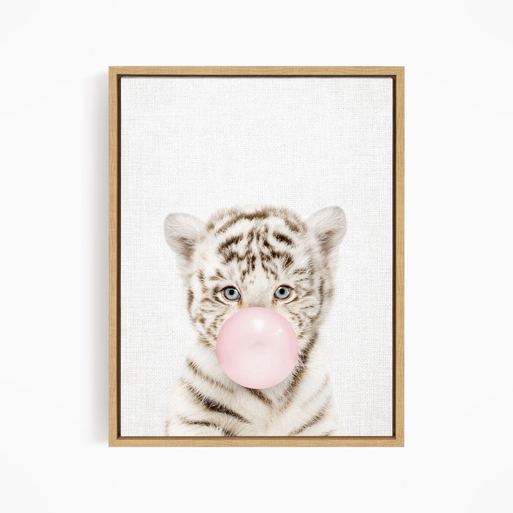 A young tiger cub blowing a bubble with a pink bubble gum bubble.