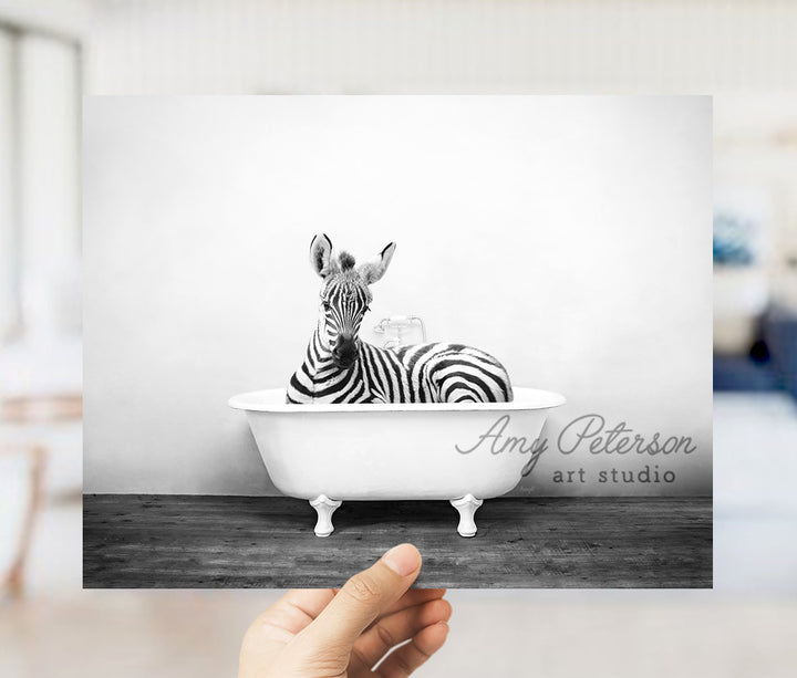 a person holding up a picture of a zebra in a bathtub