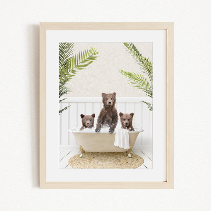 A framed image depicting three brown bears sitting in a bathtub, surrounded by green palm leaves.