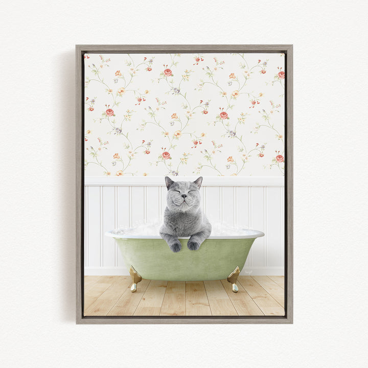 A gray cat sitting in a green bathtub, with a floral wallpaper in the background.
