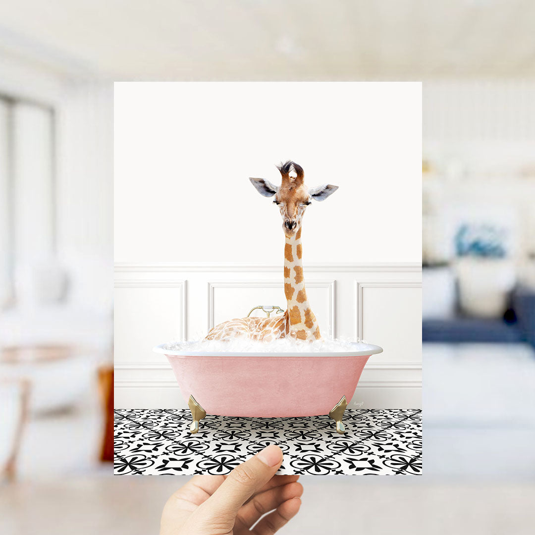 A giraffe sitting in a pink bathtub filled with bubbles, with a hand holding the image up to the camera.