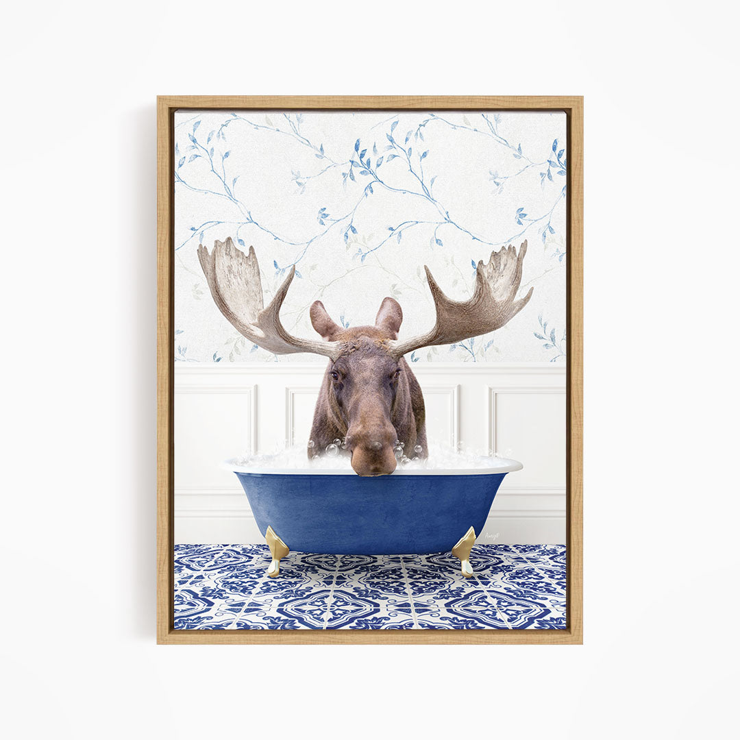 A moose with large antlers is sitting in a blue bathtub, surrounded by a patterned tile floor and a floral wallpaper background.