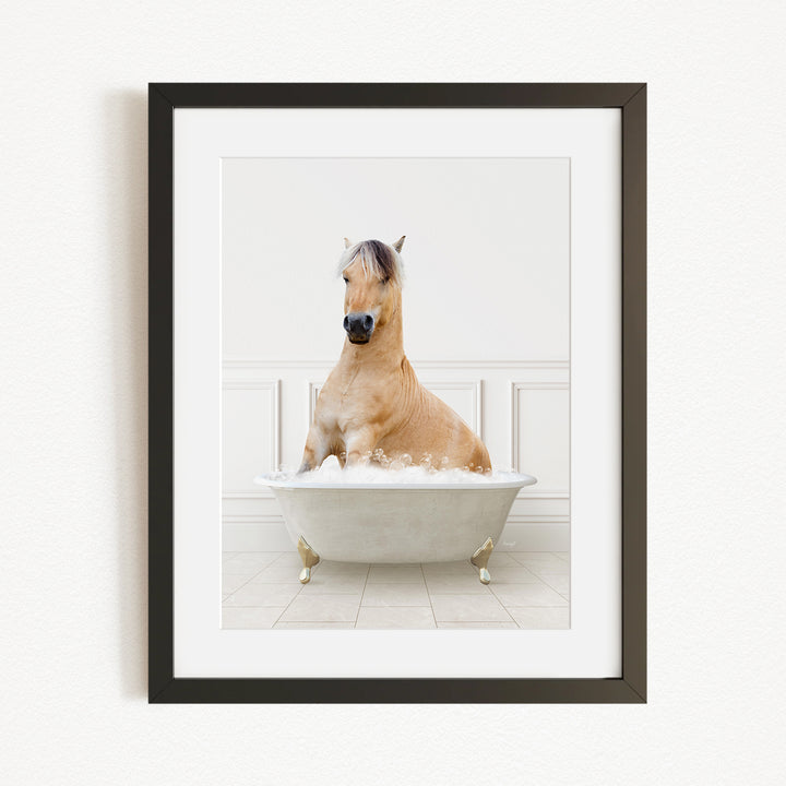 A light brown horse is sitting in a white bathtub filled with bubbles, creating a whimsical and playful scene.