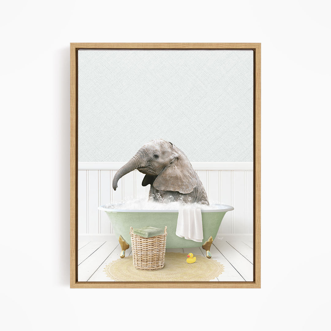 A baby elephant sitting in a green bathtub filled with water, surrounded by a basket of toys and a yellow rubber ducky.