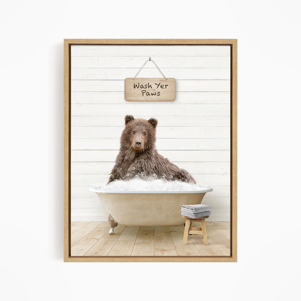 A brown bear sitting in a bathtub filled with water, with a sign above that says "Wash Your Paws".