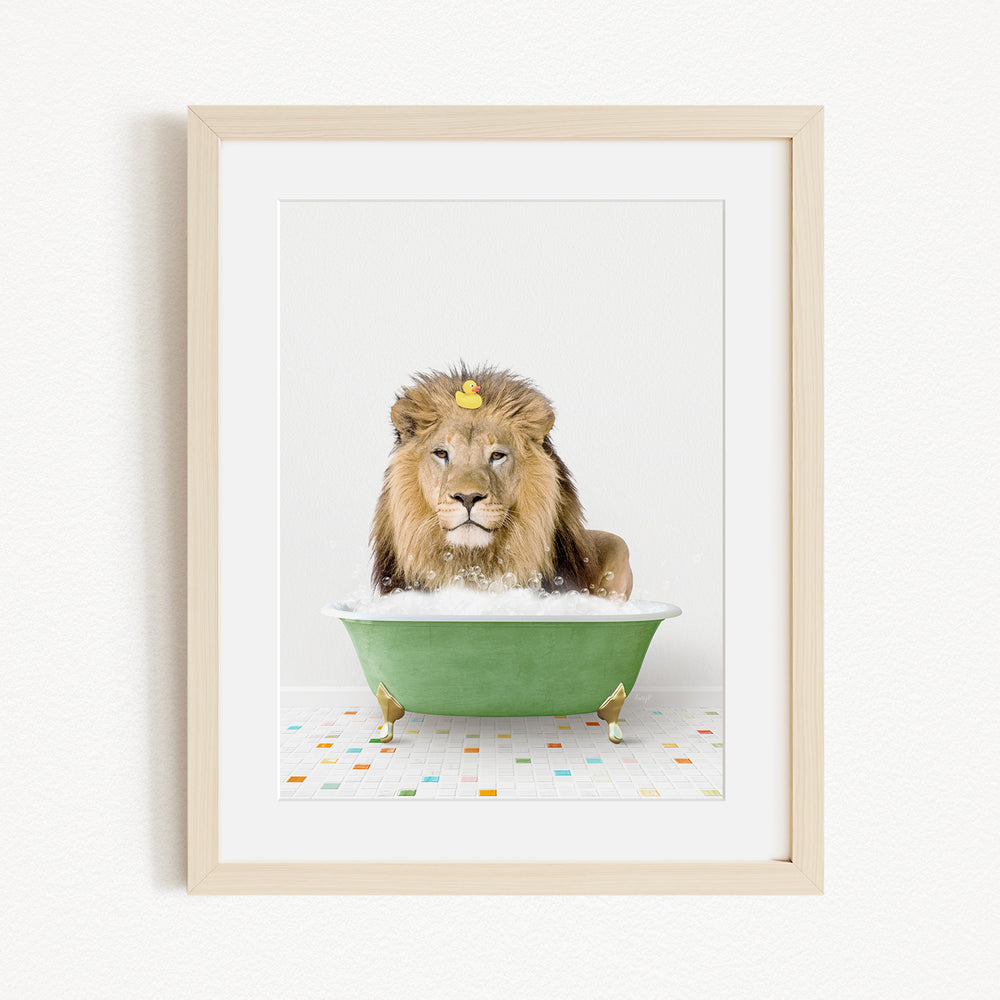 A lion is sitting in a green bathtub filled with bubbles, with a yellow rubber duck floating on the water.
