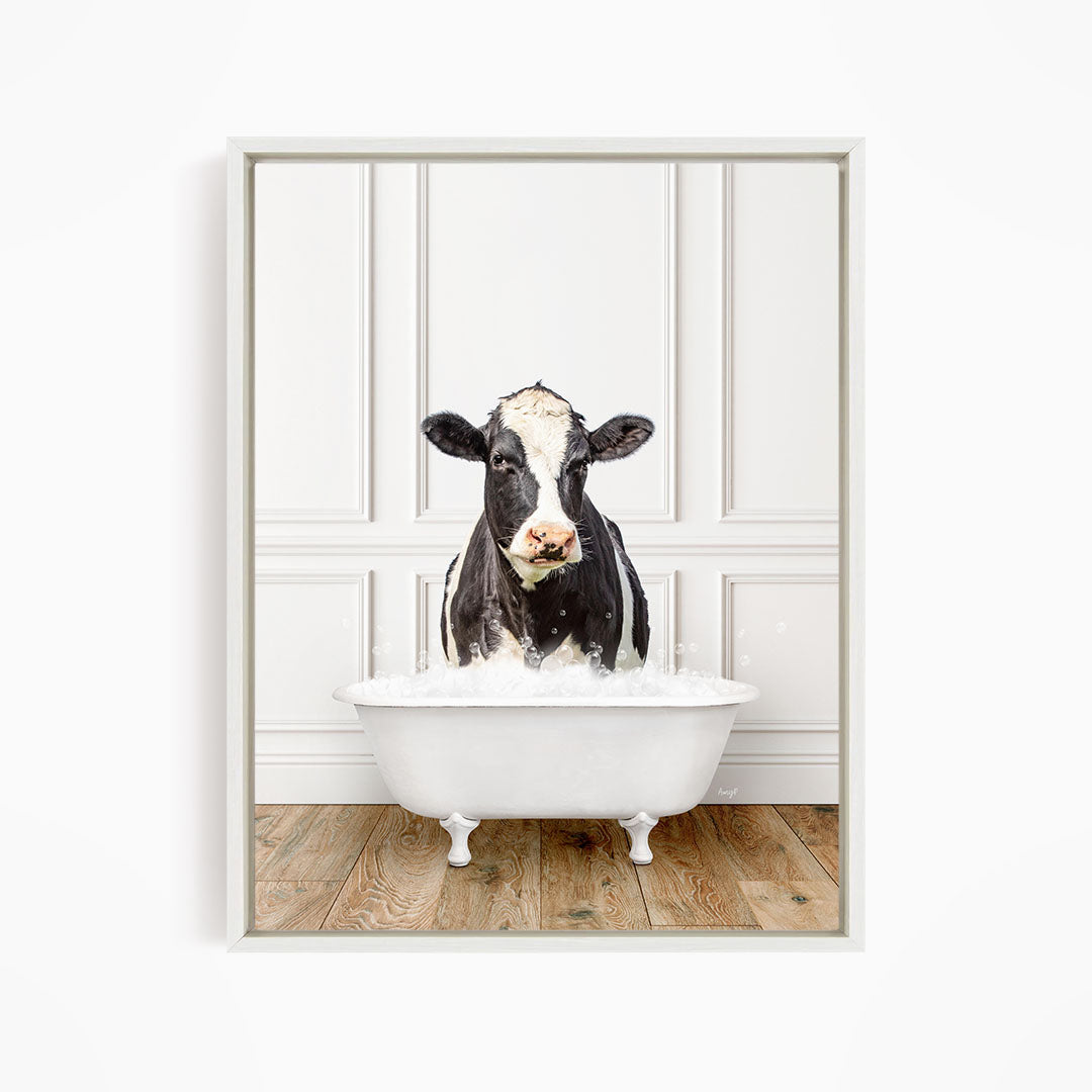 A black and white cow is standing in a white bathtub filled with water, creating a humorous and whimsical scene.