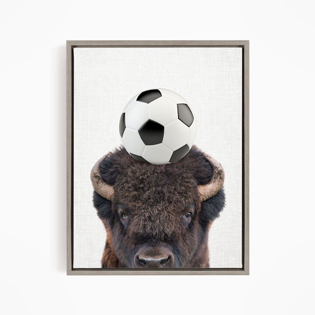 A buffalo with a soccer ball on its head.