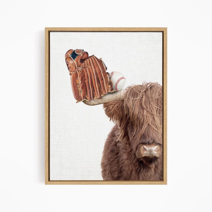 A framed image depicting a cow with a baseball glove on its head and a baseball resting on its horn.