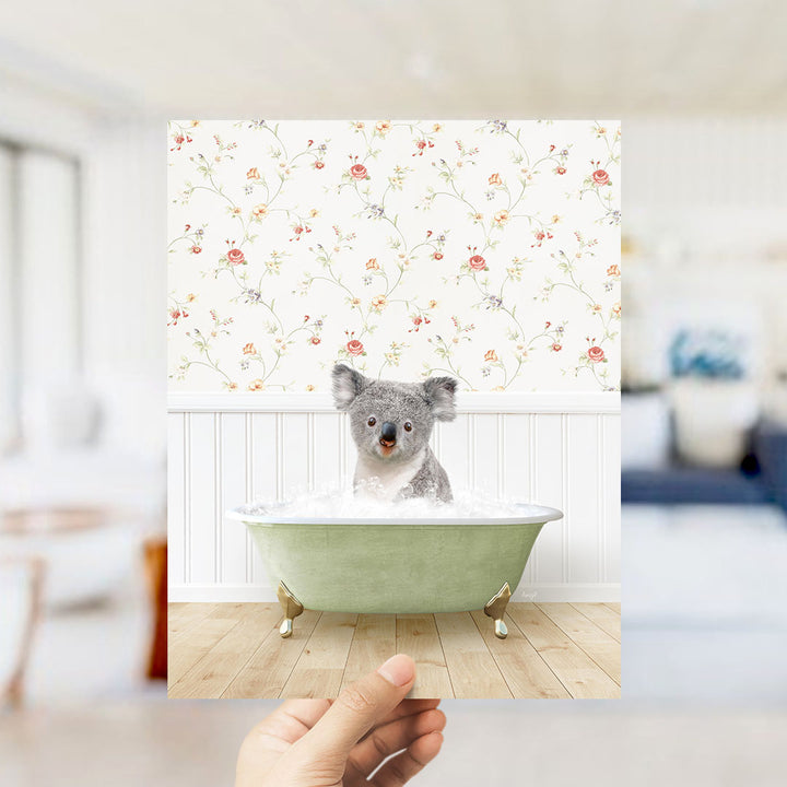 A koala bear sitting in a green bathtub filled with water, surrounded by a floral patterned wall.