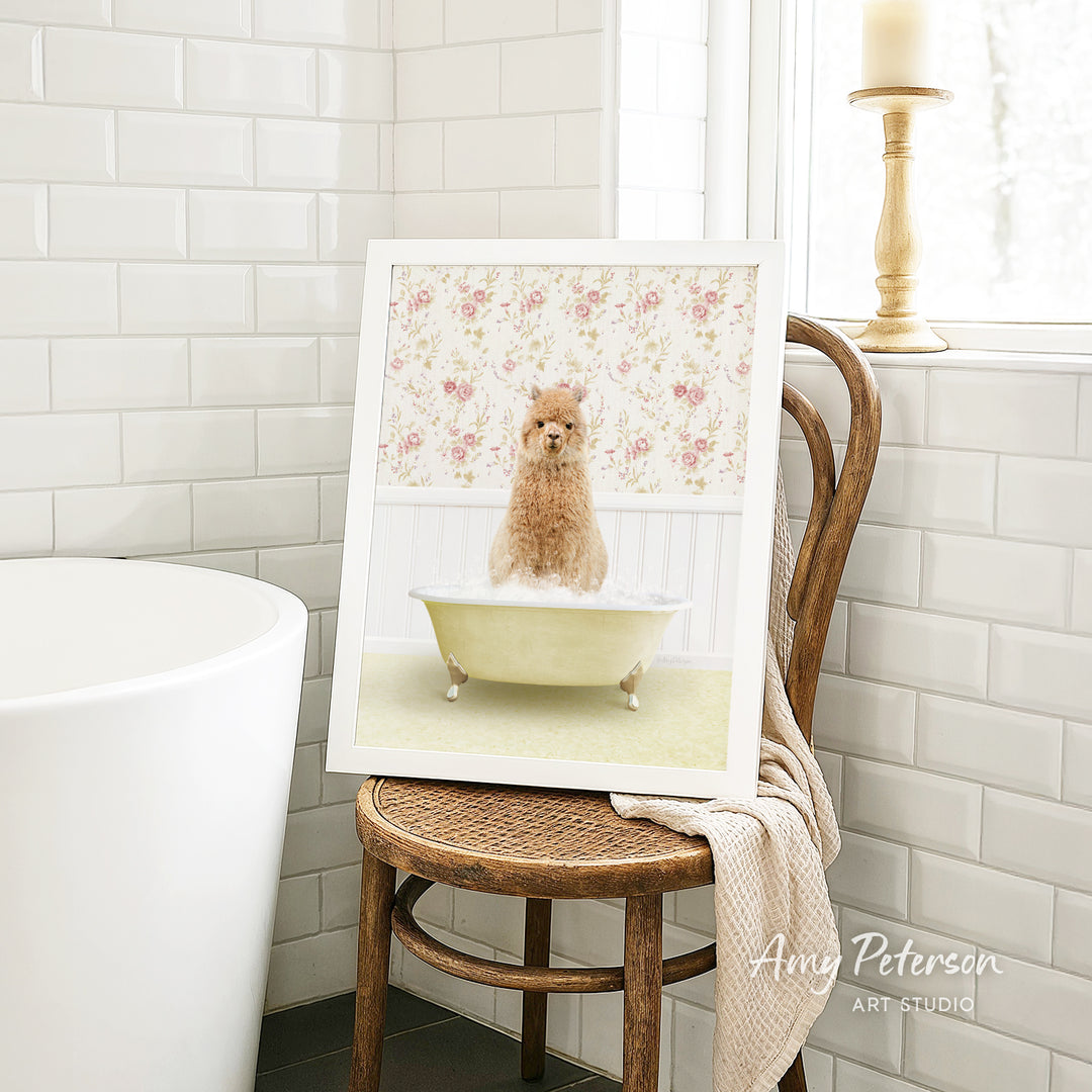 A framed image of a small dog sitting in a bathtub, surrounded by a floral pattern, is displayed on a wooden chair in a bathroom setting.