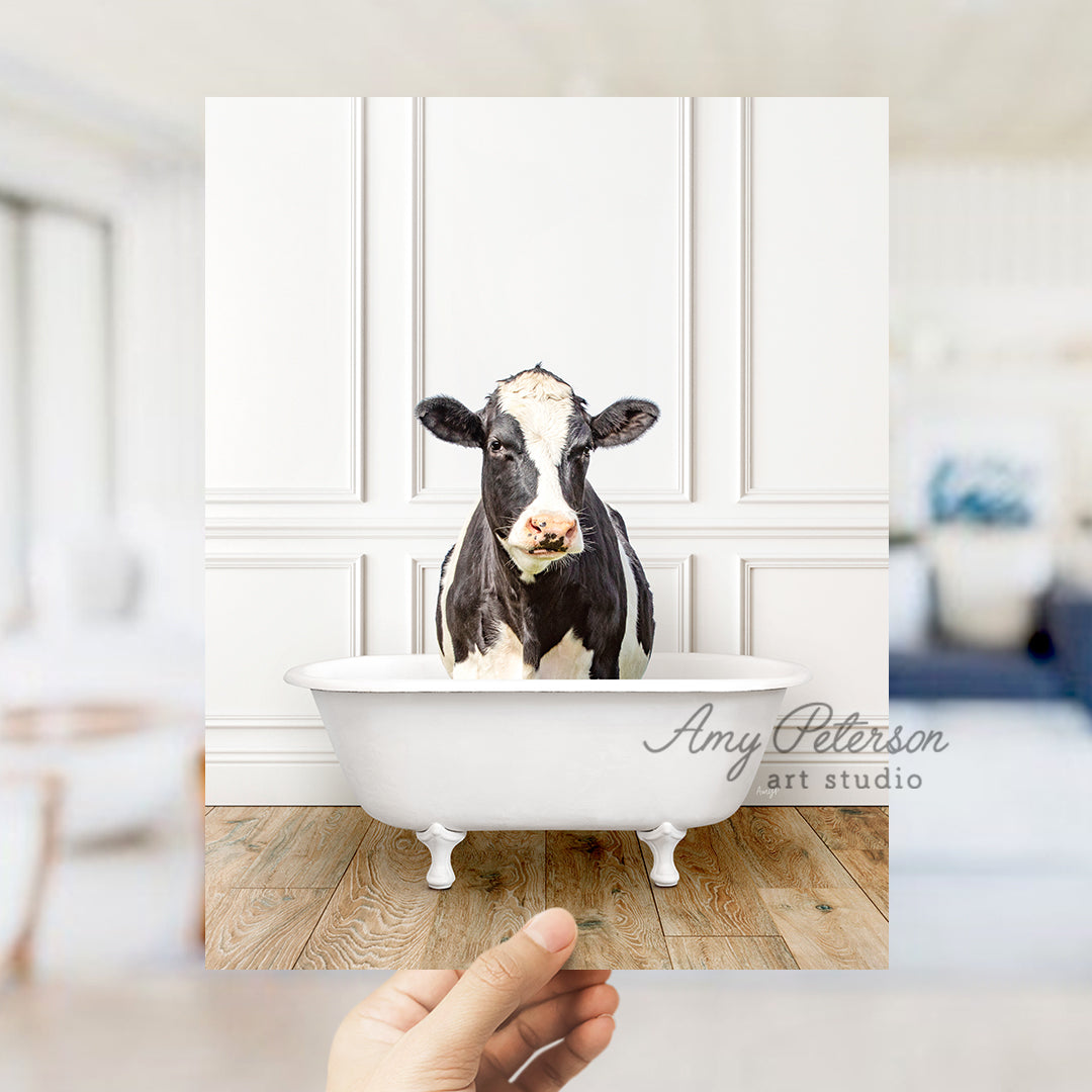 a hand holding a photo of a cow in a bathtub